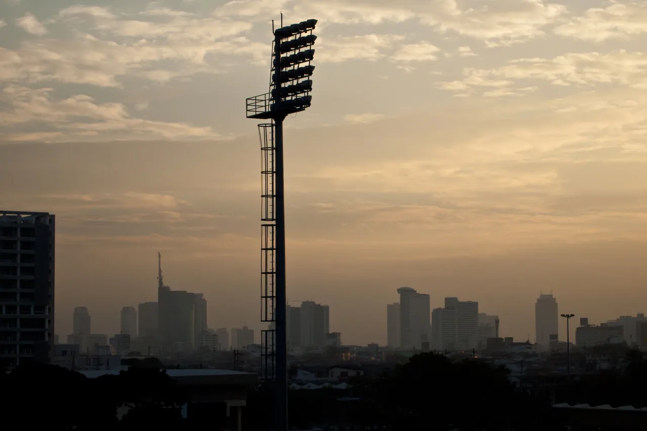 Layers of Bangkok buildings silhouetted against an orange sunset sky